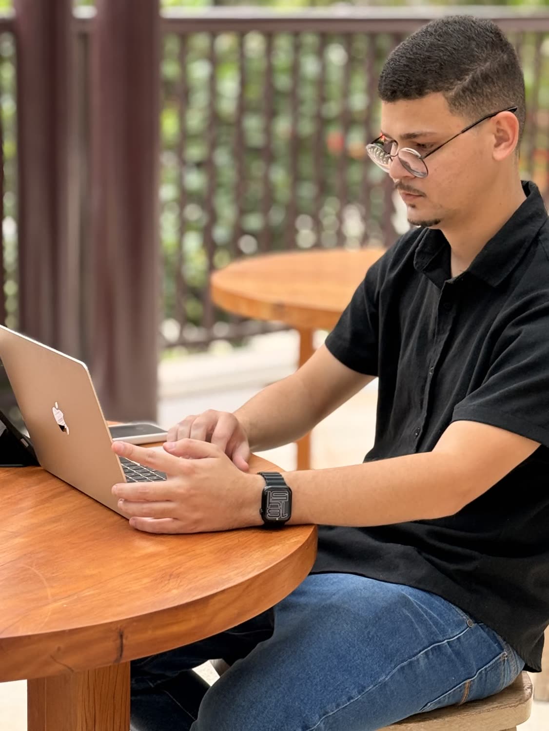 Abdeel de óculos digitando em um notebook, sentado à mesa